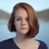 A headshot of a woman by the water and hills.