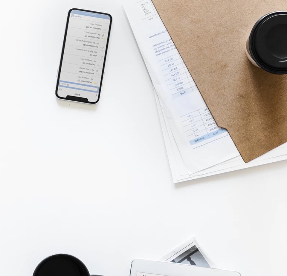 A desk with a cellphone, and papers on it.
